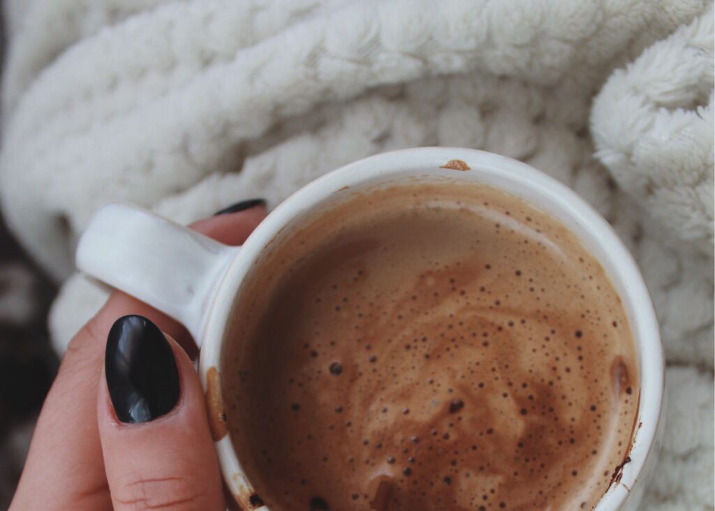 mão de mulher segurando xícara de chocolate quente