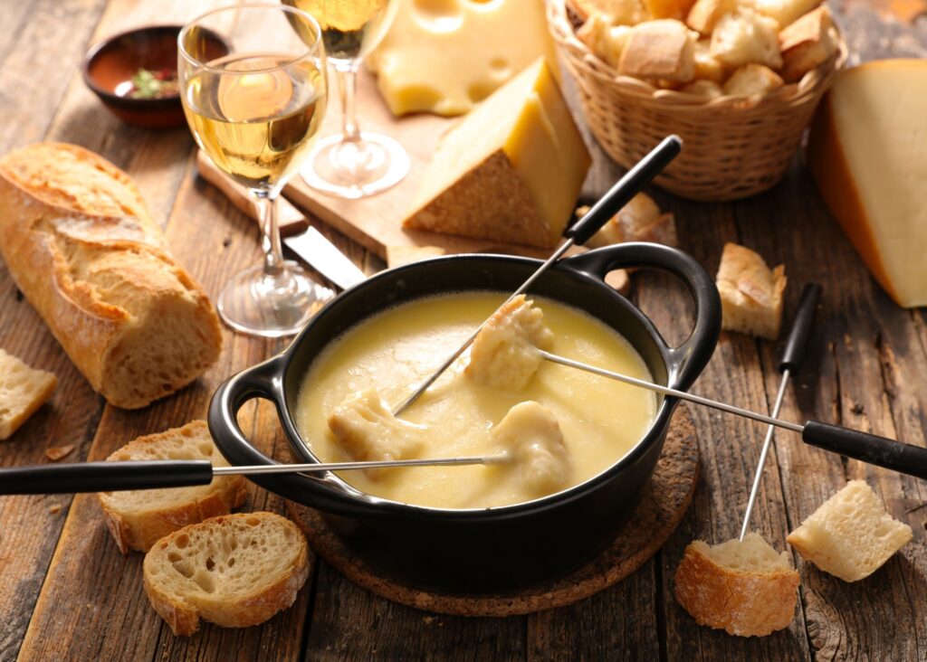 mesa com fondue de queijo, pães e vinho