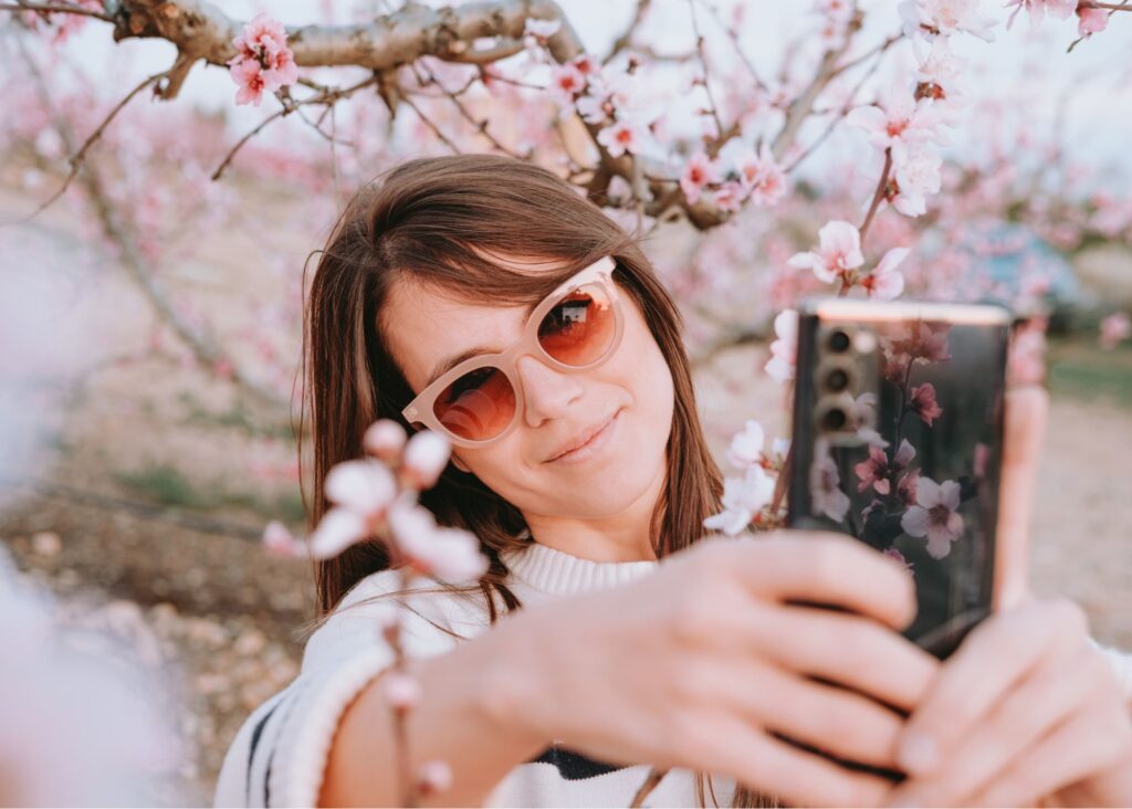 mulher tirando selfie em meio a cerejeira