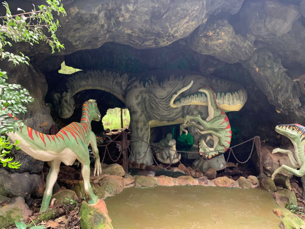 estátuas de 3 dinossauros em caverna de parque temático.