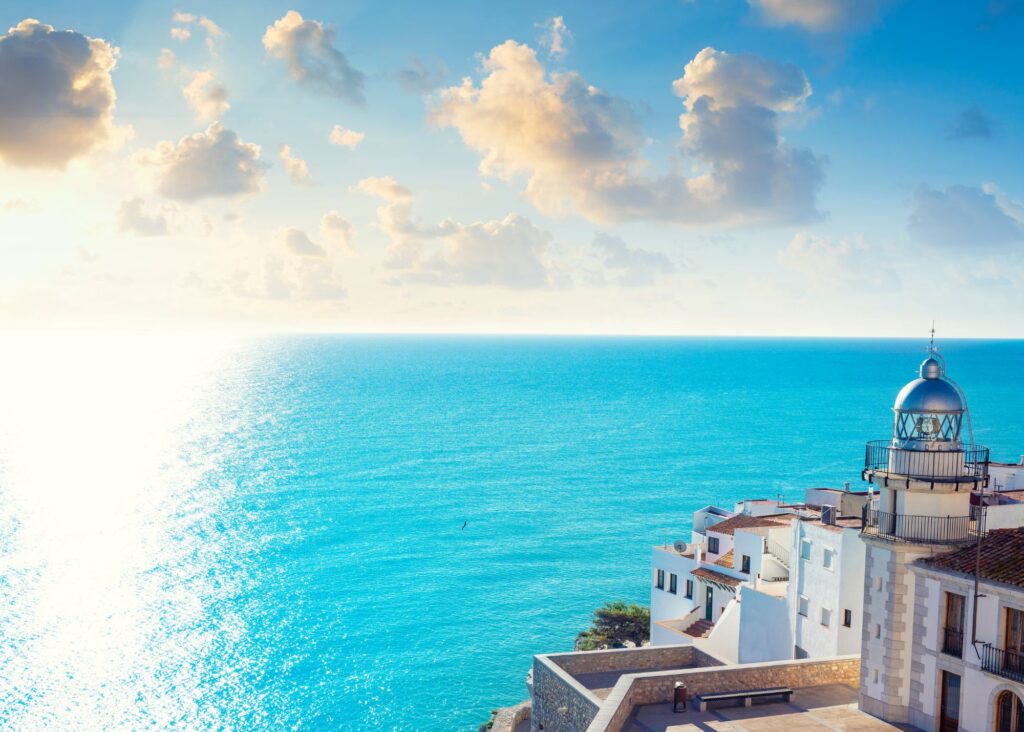 castelo branco no canto em alto de morro com visão de mar azul turquesa e pôr do sol