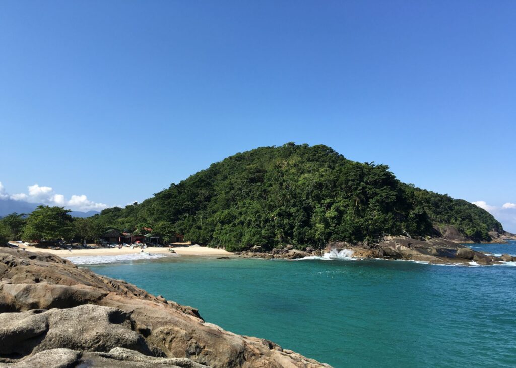 praia com vista lateral e morro verde ao fundo