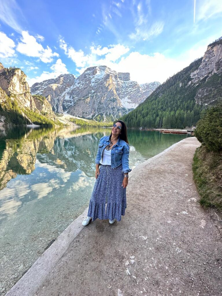 mulher sorrindo em frente a lago montanhas ao fundo