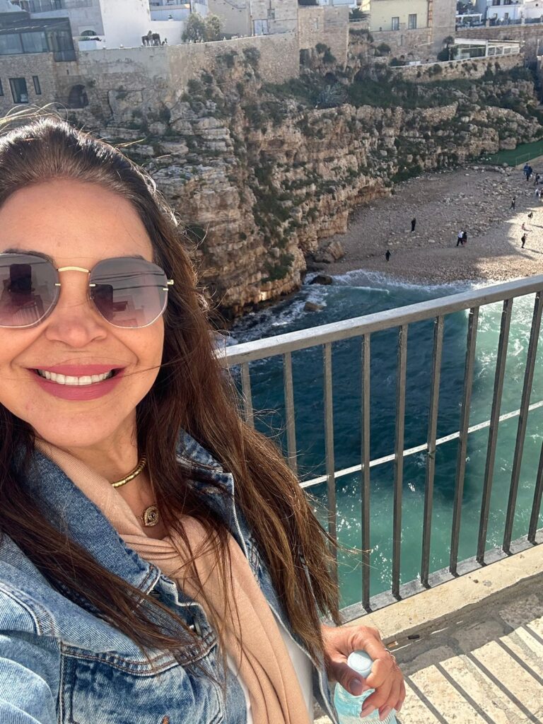 mulher sorrindo com praia e falésias ao fundo